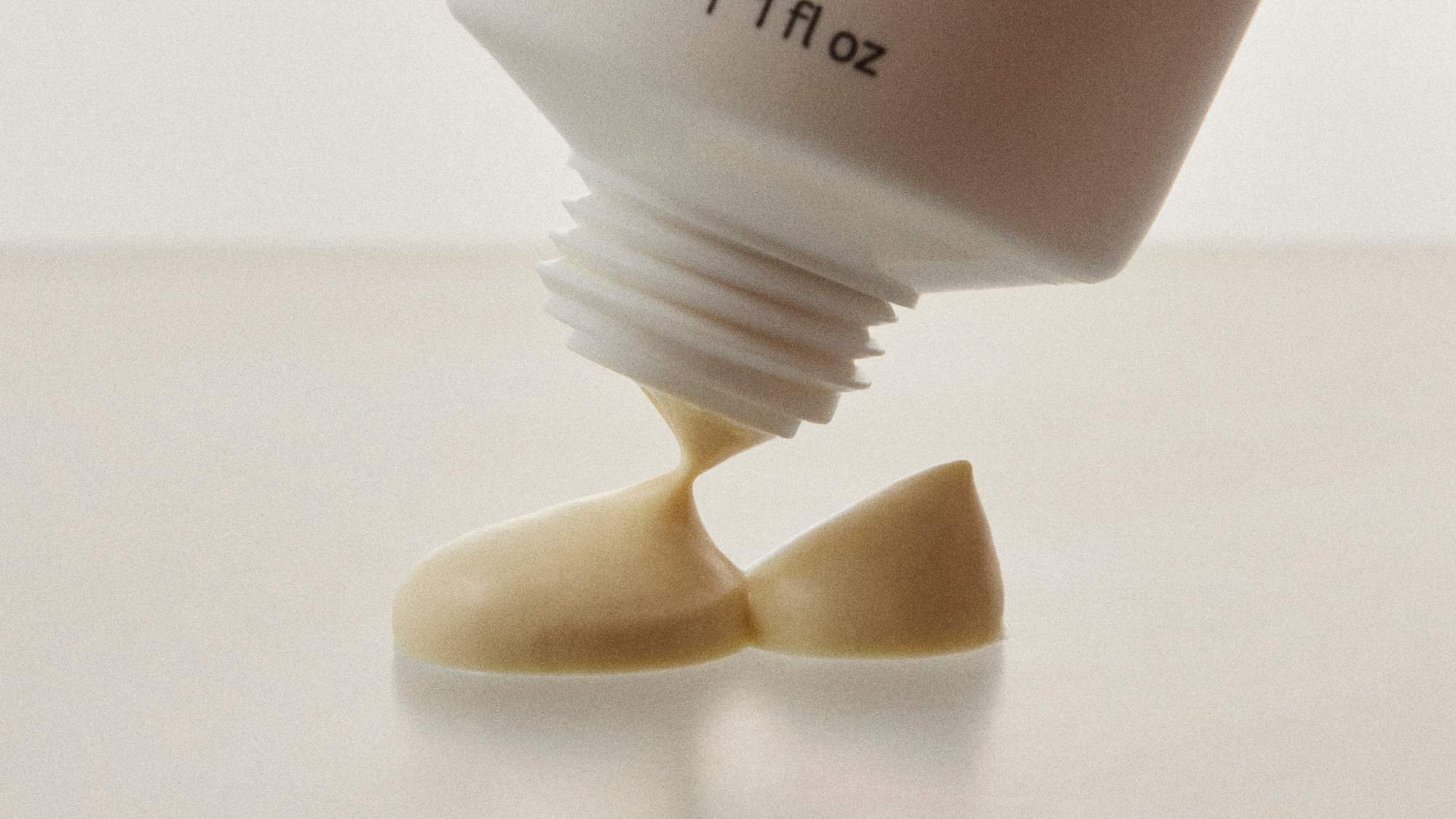 Close-up of a skincare cream being dispensed from a tube, highlighting its rich, creamy texture.